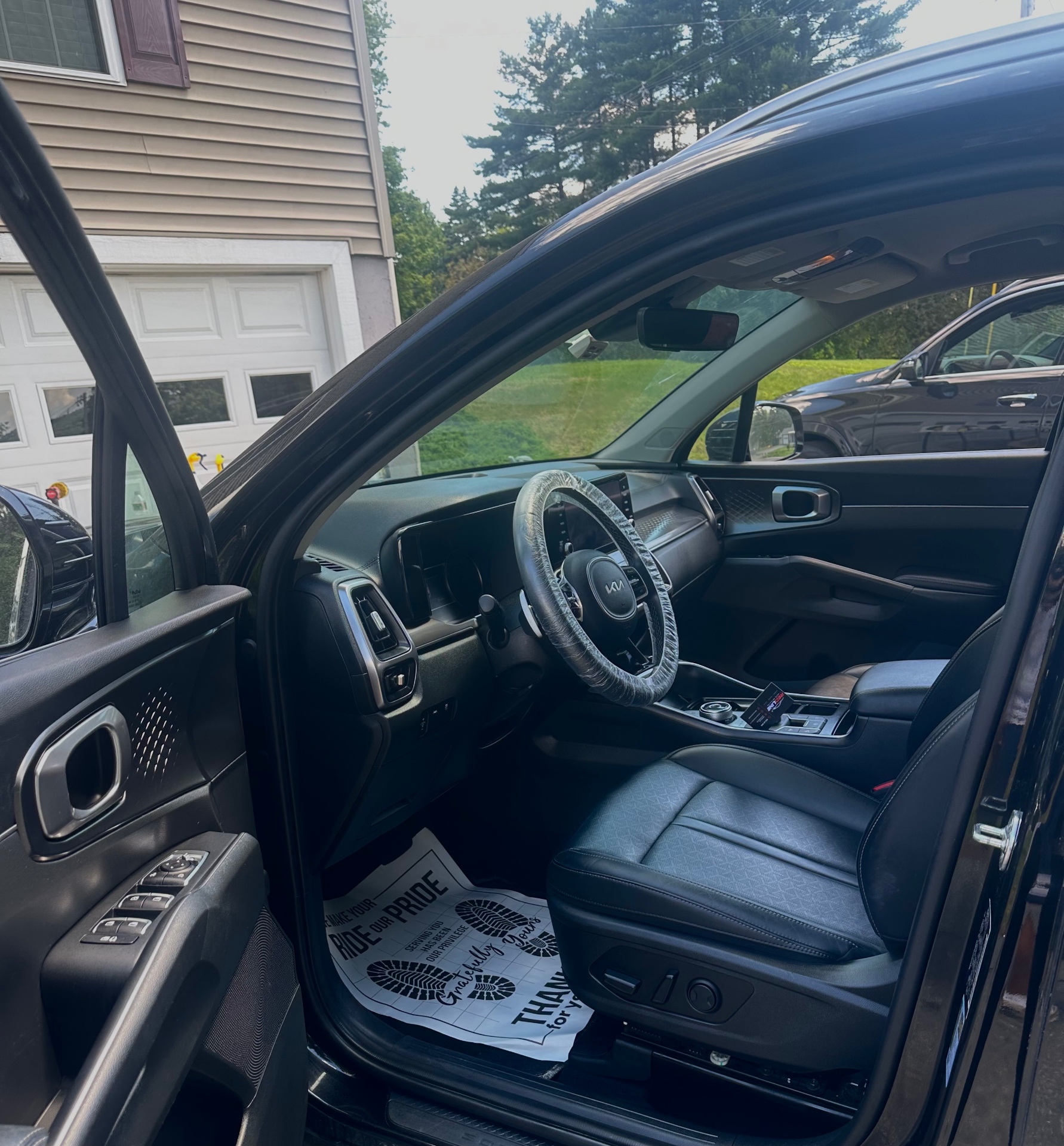 Black Kia Sorento interior after full detail with steering wheel cover and floor mat